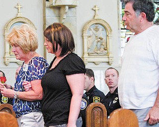Mary Kay Hartzell of Austintown carries a rose to place at a memorial service honoring Mahoning CountyÕs police offi cers who died in the line of duty. HartzellÕs son, Michael T. Hartzell, a Youngstown police offi cer, was shot and killed April 29, 2003. She is escorted Thursday inside Our Lady of Mount Carmel Church, Youngstown, by Stephanie Harchar, a county deputy sheriff and HartzellÕs fi ancŽe. Behind them is HartzellÕs father, Howard. Twenty-four offi cers have died in service since 1891.