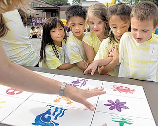 Parent volunteer Lori McGlone explains the memory-board game Wednesday at St. Charles School’s end-of-the-school-year picnic in Boardman. First-graders, from left, Ally Schwendeman, Kiet V. Lau, Brie Ruffi ng, Isabella Davis and Tim Falter learned they were supposed to stay attached, by hooking arms or holding hands, and go between two tables to correctly draw the shapes onto paper.