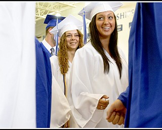 Geoffrey Hauschild|The Vindicator.A poland graduate with his fist clenched around a penny walks past Lindsay Mitchell (left) and Katarina Meris (right) on his way to receive his diplomia where he tried to drop the coin the principals palm during a handshake during Poland's 2010 Commencement Ceremony at the high school gymnasium on Sunday afternoon. Pennies could be heard hitting the floor throughout the ceremony as students backed out of the practical joke and the principal refused to accept the comical offering letting them fall to the floor.