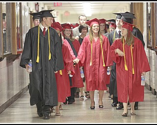 LESLIE CUSANO | THE VINDICATOR.Excited Canfield High School graduates walk down the athletic hallway at the high school before commencement exercises Sunday.