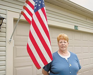 Karyn Frederick stands alongside an American flag that she flies every day of the year outside her Canfield home. It is a tradition instilled by her father, a World War II veteran. She says she is saddened that many Americans no longer hold great reverence toward the flag.