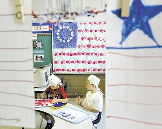 Aidan Frease, left, and Michael Vukovich, both 7 and participants at Sunny Days Child Care Center in Girard, work on a Flag Day project.