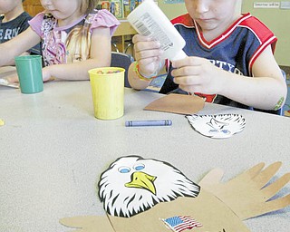 4-year-olds Faith Sullivan and Nicholas Ricottilli concentrate on gluing wings on a bald eagle, the emblem of the United States, as part of a Flag Day craft project at Lads ‘N Lassies Academy in Boardman.