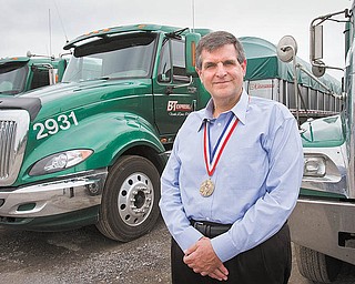 Tom Cook poses for a portrait with his 2010 Ellis Island Medal of Honor outside his office at B&T Express in North Lima.