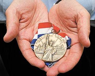 Tom Cook holds his 2010 Ellis Island Medal of Honor.