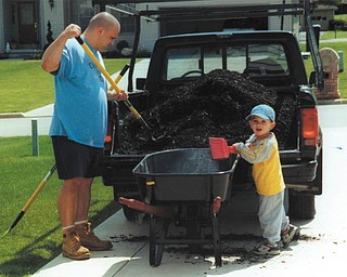 Tony Cougras of Poland is a good sport about the mulch that didn’t make it into the wheelbarrow when he was  getting a helping hand from his son, Michael.
