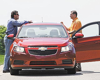 In this photo made June 9, 2010, General Motors engineers Wayne McConnell, left, director of vehicle performance integration and Brandon Vivian, performance manager for the Chevrolet Cruze confer during a road test of a pre-production model in Milford, Mich. With the Chevrolet Cruze, General Motors is on the verge of building its first decent small car. Yet it won't be easy for the automaker to win over a skeptical America. People know that Nothing Works Like a Chevy Truck, but are they willing to gamble on a company with a long history of small-car disasters. (AP Photo/Paul Sancya)