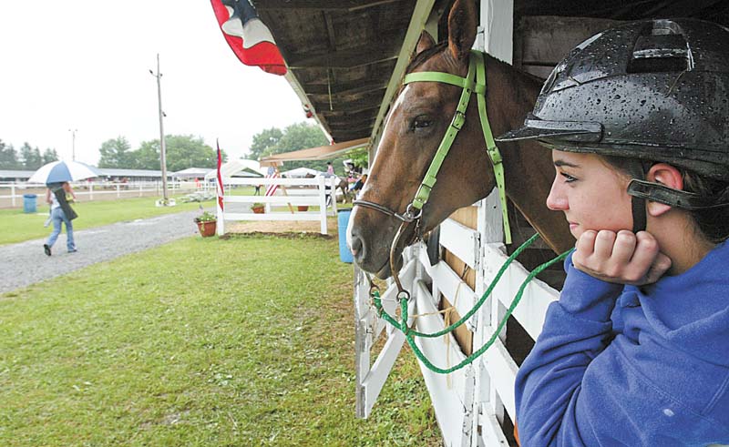 Katier Chandler, 18, of Champion and her horse "Roxie" stay dry while waiting to compete in a 4H event at the Trumbull County Fair Thursdazy. wdlewis