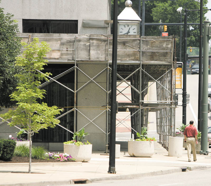 A pedestrian makes his way around scaffolding on the PNC Bank Building on Central Square in downtown Youngstown. The scaffolding was supposed to come down months ago, and the city is considering suing the buildingÕs owner to get it removed.