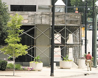 A pedestrian makes his way around scaffolding on the PNC Bank Building on Central Square in downtown Youngstown. The scaffolding was supposed to come down months ago, and the city is considering suing the buildingÕs owner to get it removed.