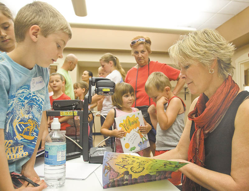 Michael Hvizdos, 7, of North Lima gets an autograph Wednesday from childrenÕs author and illustrator Cyd Moore at the Boardman Library. Moore spoke about her life and artwork to kick off the public libraryÕs summer reading program..
