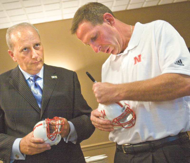 Bob Hannon, left, president and chief professional offi cer of the United Way of Youngstown and the Mahoning Valley, watches as University of Nebraska football coach Bo Pelini autographs miniature football helmets during the organization’s “Champions Among Us” banquet Tuesday at Antone’s Banquet Centre in Boardman. Pelini, a graduate of Cardinal Mooney High School and The Ohio State University, spoke about how pride in his roots molded him into a successful coach.