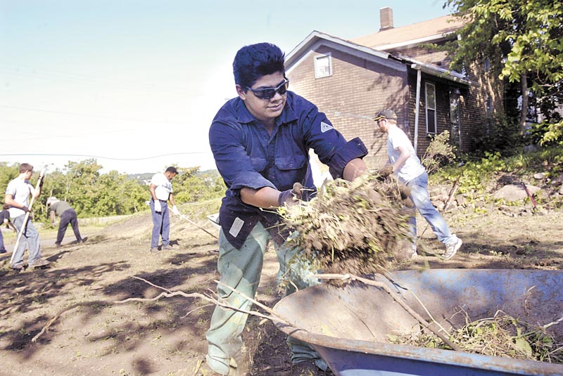 Lien Forward and V&M Star organized a group of about 30 volunteers to spruce up a vacant lot at the corner of Oakland Avenue and Columbia Street in Youngstown’s Brier Hill area Wednesday. Above, Robert Flores, a V&M Star employee and member of V&M’s Sons and Daughters program, helps clear brush from the lot.