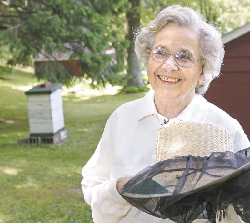 Mary Brashen, a beekeeper for some 30 years, stands near one of her five bee hives at her home in Hubbard Township. Brashen, who puts the tag of "Merry Bee" on her jars of honey, recently was called to Hubbard Area Library to collect a swarm. .