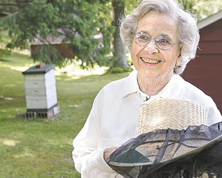 Mary Brashen, a beekeeper for some 30 years, stands near one of her five bee hives at her home in Hubbard Township. Brashen, who puts the tag of "Merry Bee" on her jars of honey, recently was called to Hubbard Area Library to collect a swarm. .