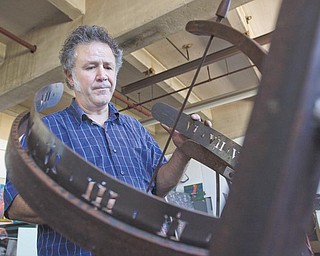 Sculptor Tony Armeni adjusts a sundial prototype in his studio on Mahoning Avenue. Armeni is one of more than 40 artists taking part in the Summer Festival of the Arts at Youngstown State University this weekend. The Youngstown Jazz Festival and the Tour of the Valley also are downtown this weekend.which has been dubbed the “Biggest Weekend of the Summer.”