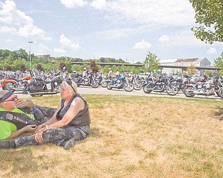 Gary Mathews of Ellsworth, a member of the Blue Knights of Ohio, and Patty Cleburn of Columbiana relax on the grass as they await the start of the eighth annual memorial motorcycle run. The Blue Knights co-sponsored the run.