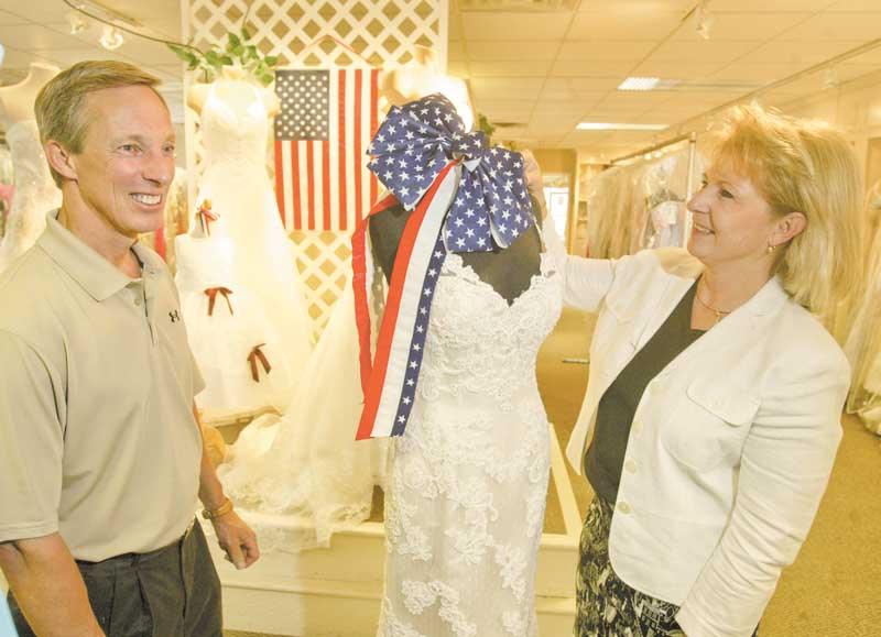 Mark and Lorraine Fulks, owners of Treasured Moments Bridal and Formal in Boardman, show off bridal gowns. The store will participate on Friday in Brides Across America, a non-profit program that distributes free gowns to military brides.