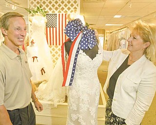 Mark and Lorraine Fulks, owners of Treasured Moments Bridal and Formal in Boardman, show off bridal gowns. The store will participate on Friday in Brides Across America, a non-profit program that distributes free gowns to military brides.
