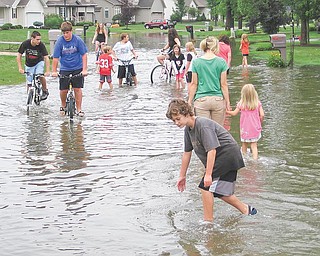 Neighborhood kids wade through water on Laura Lane in Cortland on Tuesday afternoon. Three hours after a burst of rain hit the neighborhood, parts of Laura and a nearby street were still flooded.