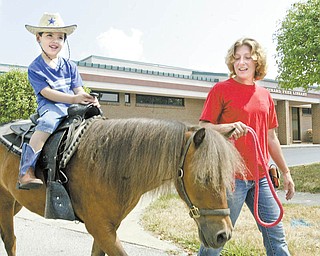 David Van Pelt, 4-year-old son of Kathy and Ron Van Pelt of Girard, enjoys a ride on Charlie Brown led by Brandy Kemmer of PonyTails of Canfield. The Girard Free Library offered the free pony rides Wednesday.