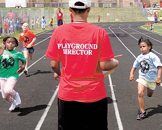 Under the watchful eye of a playground director, Leah Harris, 6, left, and Jalaya Brown, right, both of Youngstown, race to the finish line in the 50-meter dash at the Youngstown Park and Recreation Department’s annual track and field day at Cardinal Mooney High School. Behind Leah is Ana’Lyse Cole, 7, of Struthers. The unidentified director recorded the order of finish Thursday. 
