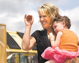 Susanne Koenig holds her daughter Marina, 3, as she waves at her other daughter, Mackenzie, 5, who is walking with the princess pageant behind The Little King and Little Queen, during the 12th Annual Procession for the Our Lady of Mount Carmel Italian Festival proceeds down Via Mount Carmel Avenue.