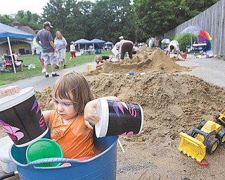 Sophia Danchise, 2, of Youngstown takes a break from sand sculpting to play in a bucket during Sunfest in Mill Creek Park on Sunday.