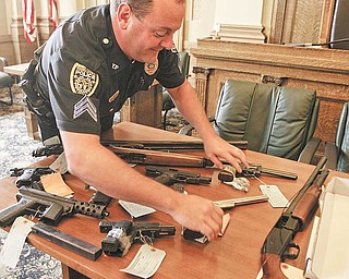 Det. Sgt Mike Lambert places a Smith and Wesson on a table. Youngstown and Warren officials announce the first wave of federal indictments to come out of the Violence, Gun Reduction Interdiction Program. Officers have confiscated 41 guns and indicted four people since the coordinated local and federal offensive against crime in the Mahoning Valley began July 4.