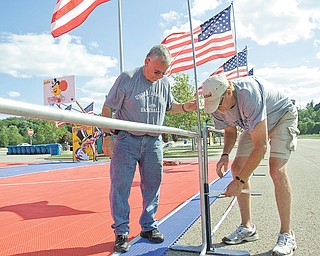 Greg Finnegan, left, and Dolph Carroll of Youngstown Christian School set up fl ags in preparation for Saturday’s Gus Macker tournament in the parking lot at the Covelli Centre. Action begins early in the morning and lasts throughout the day.