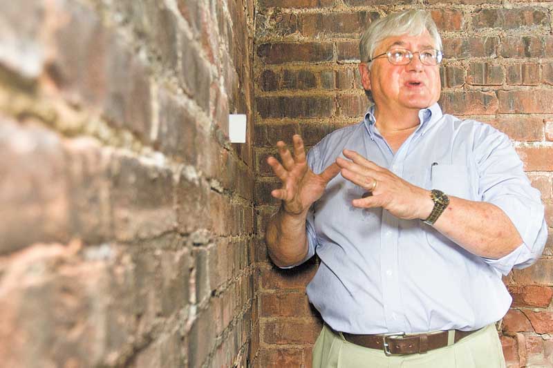 William Kostelic, consultant for The 4M Co., places a business card between two bricks inside the Mahoning County Courthouse catacombs to show how much the walls have shifted. Kostelic said the chambers under the courthouse statues need to be stabilized to prevent eventual collapse. The 4M Company will begin taking down the statues and the five granite slabs they sit on in September as a temporary safety precaution.