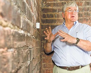William Kostelic, consultant for The 4M Co., places a business card between two bricks inside the Mahoning County Courthouse catacombs to show how much the walls have shifted. Kostelic said the chambers under the courthouse statues need to be stabilized to prevent eventual collapse. The 4M Company will begin taking down the statues and the five granite slabs they sit on in September as a temporary safety precaution.