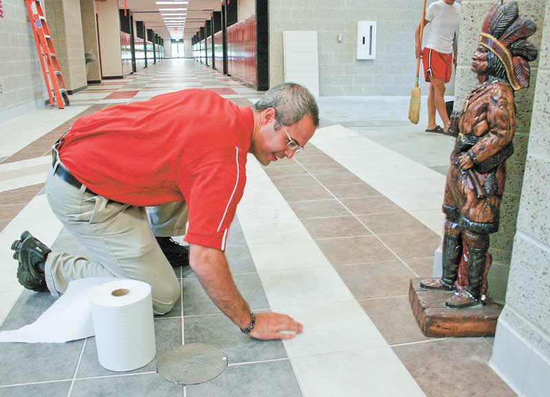 William Ryser, senior high principal at the new Girard Junior/Senior High School, pitches in to clean the fl oor after an inadvertent spill as a statue of an Indian, the Girard mascot, “oversees.” Ryser said he thinks the new building will inspire students and the sleek surroundings will enhance learning.