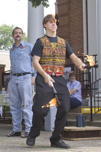 LISA-ANN ISHIHARA | THE VINDICATOR..Travis Fessler, left, speaks to the crowd as his younger brother, Erik Kloeker , both of "The Pickled Brothers" juggles a teaser act at the Northside Farmers Market for upcoming performances on the corner of Elm St and Illinois Ave, across from Wick Park (in front of First Unitarian Universalist Church).