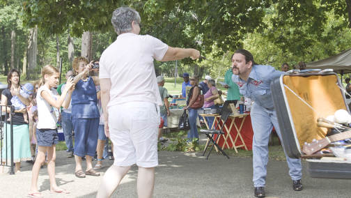 LISA-ANN ISHIHARA | THE VINDICATOR..A volunteer pulls a swore out of Travis' mouth during his teaser performance at Northside Farmers Market for upcoming events in Youngstown. He is one half of "The Pickled Brothers."