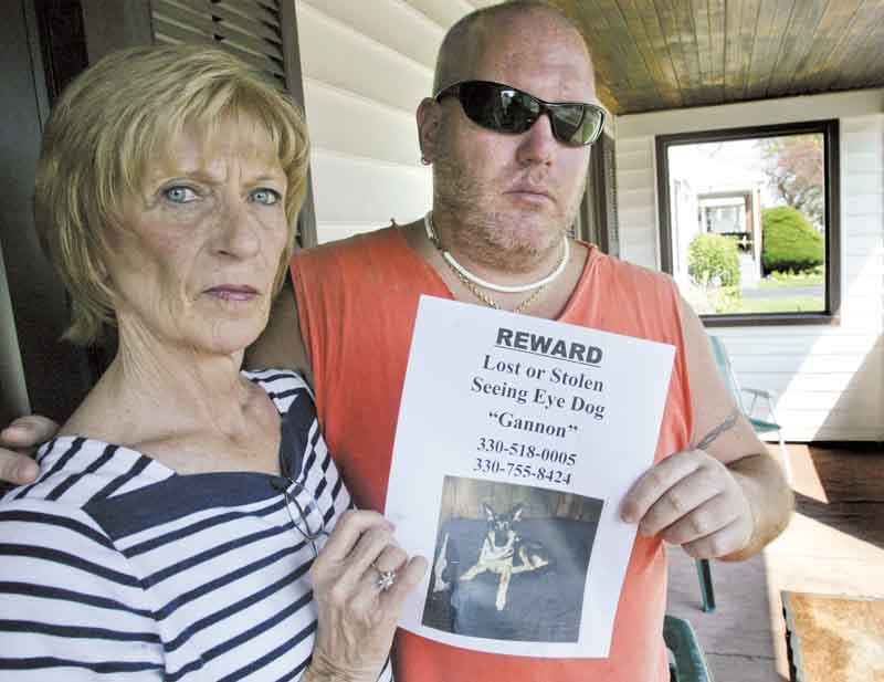 Sam Vona of Struthers, who is blind, and his mother, Jo Ann, hold one of the posters sheÕs put  up, seeking help and offering a reward to find Gannon, SamÕs seeing-eye dog, who ran off on Saturday..