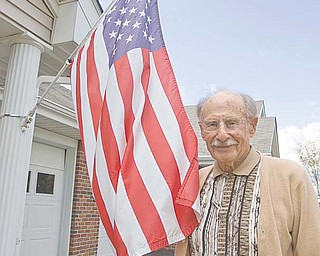 Ray Braidich, a World War II veteran, stands by the American flag mounted outside his home at Shepherd of the Valley-Poland. Braidich thinks there should be a more-dignified vessel in which to burn worn flags, noting that a trash can or burn barrel is often used in flag-disposal ceremonies.