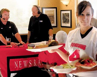 Sarah Kotch of Jackson-Milton delivers food as Eric Wolford, YSU’s head football coach, left, speaks with Bob Hannon, president of United Way of Youngstown and the Mahoning Valley, while on the radio during the Score a Touchdown for the United Way event at O’Charley’s in Boardman on Thursday.