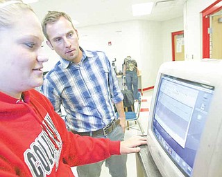Jayson Yeagley, right, a Columbiana High School teacher and student Abby Hertel work on a computer used in the school’s video laboratory.