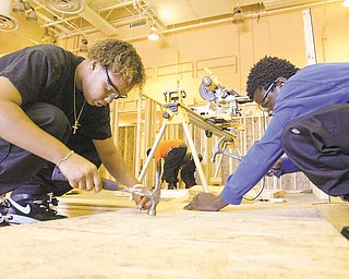 Juniors Eva Baker, left, and Aaron Clinkscale, with Choffin’s construction technology program work on the house, which will become home to a Struthers family.