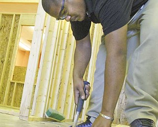 Laquail Brooks, a junior and a student in the construction technology program at Choffin Career and Technical Center, hammers in nails on the frame of a house for Habitat for Humanity of Mahoning County.