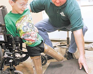 Nicholai “Kolya” Denykin, 10, of the Renewal Orphanage in Dimitrov, Russia, undergoes a fitting for prosthetic legs with Craig Svader of Advanced Anatomical Design, licensed prosthetic, orthotic and pedorthic professionals in Canfield and Girard. Kolya was born without legs below the knees.