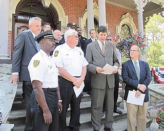 Law-enforcement officers and others who carried out the Violence and Gun Reduction Interdiction Program law-enforcement initiative this summer in the Mahoning Valley stand on the front steps of Warren City Hall during a press conference to declare that V-GRIP was an unqualified success, taking more than 150 firearms off the street and resulting in the arrest of 600 people. Shown in the front row Thursday are, from left, Youngstown Police Chief Jimmy Hughes; Warren Police Chief Tim Bowers; Steven M. Dettelbach, the U.S. Attorney for the Northern District of Ohio; and Warren Mayor Michael O’Brien.