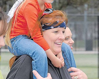 Danielle Houshton crosses the finish line with Emma Ames on her shoulders during Sunday morning’s 19th annual MS Super Walk that began in Mill Creek MetroParks’ James L. Wick Recreation Area.