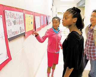 Sixth-graders Rayonna Abron-Booth, 11, left, and Monique Abron, 10, along with Tyler Abron, 14, check out artwork created by Rayonna during the ribbon-cutting ceremony and open house at the new Woodrow Wilson Middle School on Sunday afternoon.
