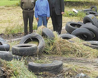 John Lesnansky, left, Helen Jackson and the Rev. Nicholas Mancini survey tires that will be cleaned up on Wilson Avenue across from St. Stephen of Hungary Church. The former Lewis Auto Body shop has been a popular illegal dumping ground since it closed in the 1970s.