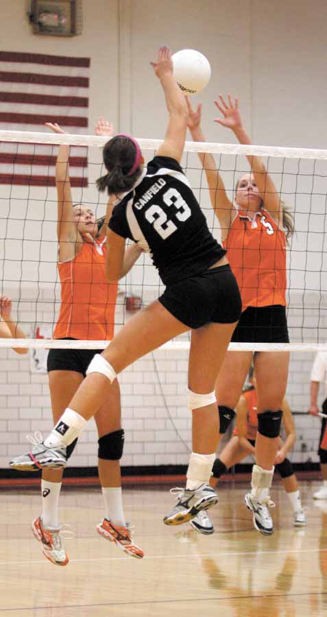 VOLLEYBALL - (23) Hannah Milstead of Canfield spikes the ball as (7) Katie Kennedy and (5) Larissa Santangelo go for the block Monday night. - Special to The Vindicator/Nick Mays