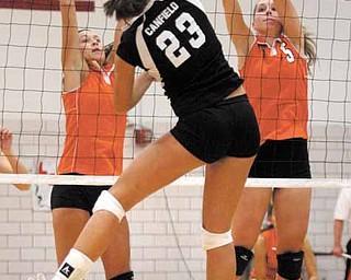 VOLLEYBALL - (23) Hannah Milstead of Canfield spikes the ball as (7) Katie Kennedy and (5) Larissa Santangelo go for the block Monday night. - Special to The Vindicator/Nick Mays