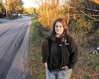 Lindsey Baird stands along a bend in Columbiana Road (County Road 62) near the intersection with Kibler Road. Baird lives at the curve and is concerned about the number of accidents at that location — five crashes this year, one of them fatal. Over Baird’s shoulder is a memorial for Matthew A. Timmins, 22, who died from injuries sustained in a two-vehicle accident at the bend Sept. 26.