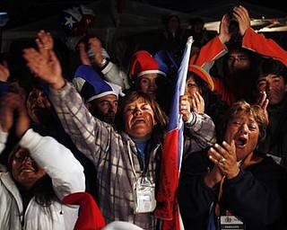 Relatives and friends of trapped miners celebrate while watching on a TV screen the rescue operation of Florencio Avalos at the camp outside the San Jose mine near Copiapo, Chile, late Tuesday Oct. 12, 2010. Thirty-three miners became trapped when the gold and copper mine collapsed on Aug. 5. (AP Photo/Natacha Pisarenko)